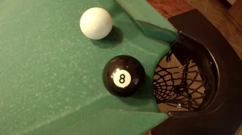 Player successfully hits 8 ball in corner pocket on a green pool table Stock Footage 46893143