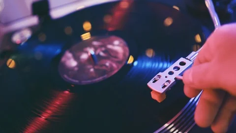 The player vinyl close-up on a background of red and blue lights. A man's hand Stock Footage 91710357