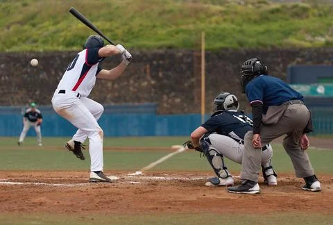 Players playing baseball while standing on field Stock Photos