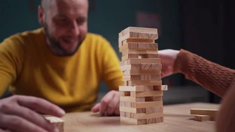 Players stack wooden blocks in a challenging game of precision and strategy on a 動画素材 276410335