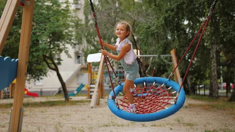 Playful active kid swinging on round rope swing on playground, having fun Video stock 137536241