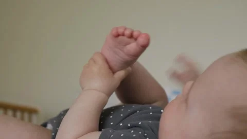 Playful Baby Joyfully Exploring Their Tiny Feet with Curiosity Stock Footage 305600239