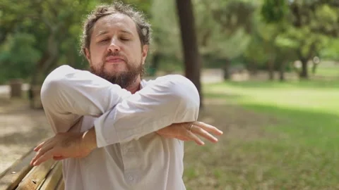 Playful bearded man dancing and making funny faces in a park Vídeos de archivo 323301554