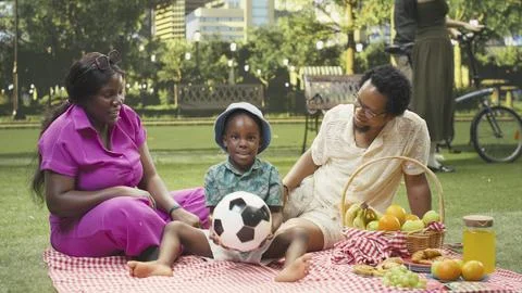 Playful boy playing catch and throwing ball at parents during picnic Stock Photos