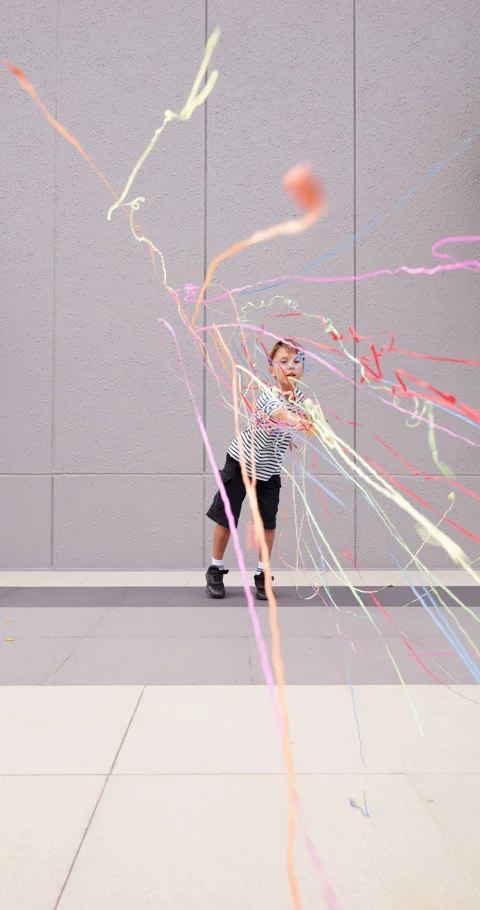 Playful child throw streamer confetti towards camera, slow motion Stock Footage 304160168