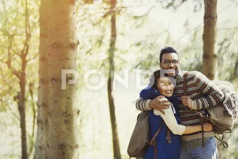 Playful couple with backpacks hugging hiking in woods Stock Photos