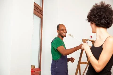 A playful couple having fun while painting apartment Stock Photos