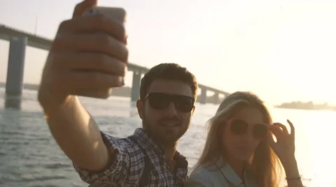 Playful couple taking photographs on the river bank Stock Footage