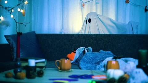 Playful ghost appears and dances in a room decorated for a fun Halloween celebra Stock Footage 344833642