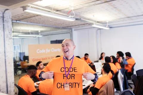 Playful hacker with t-shirt coding for charity at hackathon Stock Photos