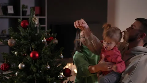 Playful hyperactive Caucasian daughter decorating Christmas tree with parents in Stock Footage 219907240