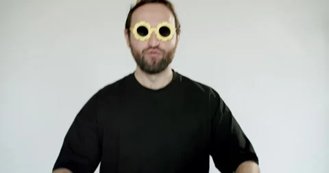 Playful Man Dances and Makes Funny Faces in Studio with Party Hat and Sunglasses Stock Footage 344269991