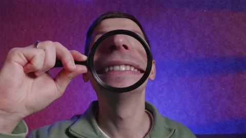 Playful man making funny faces with magnifying glass Stock Footage 333757065