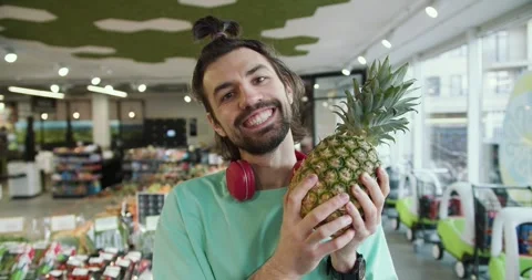 Playful Pineapple Fun: Young Man's Hilarious Antics in Green T-Shirt at the Video stock 243454109