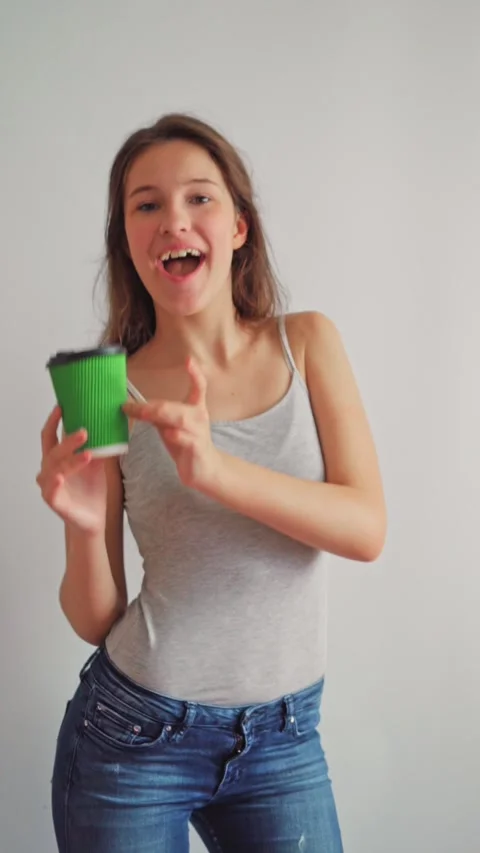 Playful student dancing with coffee while looking at camera on white background. Stock Footage 312640158
