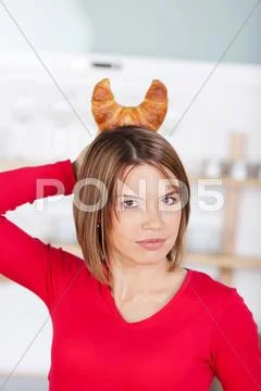 Playful woman holding a croissant as horns Stock Photos