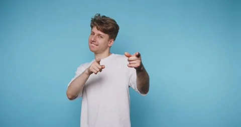 Playful young man points at the viewer with both fingers while smiling, usi.. Stock Footage 313281090