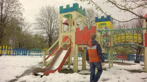 On the playground a boy is played. It's snowing. Early spring. Stock-Footage 74868209