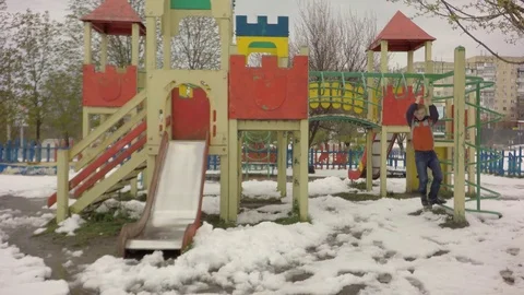 On the playground a boy is played. It's snowing. Early spring. 스톡 동영상 74869588