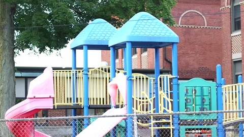 Playground, brick building, tree, chain link fence Stock Footage 304367529