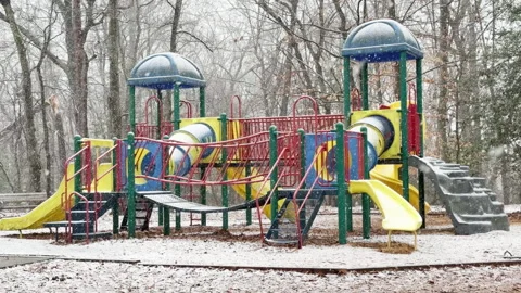 Playground equipment catches slow falling snowflakes on this snow day Stockbeeldmateriaal 334802657