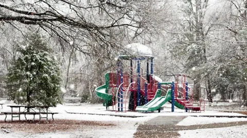 Playground equipment catches slow falling snowflakes on this snow day Stockbeeldmateriaal 336573551
