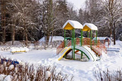 Playground Slide Surrounded by Trees Covered with Snow Stock Photos