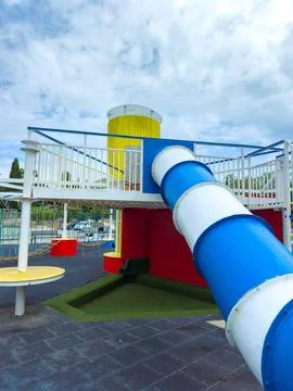 A playground structure features a tall blue slide and a yellow viewing tower. Stock Photos