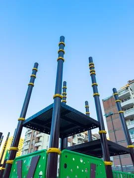 A playground structure features tall poles and platforms in a residential are Stock Photos
