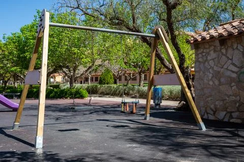 Playground swings while surrounded by green trees and cheerful atmosphere on Stock Photos
