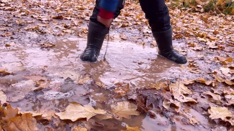 Playing and jumping in muddy puddle on an autumn day. Stock Footage 255772437