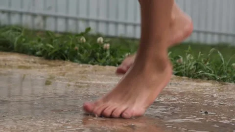 Playing barefoot through the rain on a wet surface in a garden Vidéo 284767259