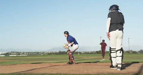 Playing baseball, catcher jumping to catch ball while runner slides to base Stock Footage 297343584