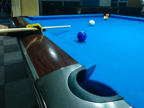 Playing billiard - A shot of a man playing billiard on a blue pool table Stock Photos