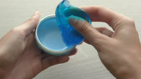 Playing with blue slime taken from a macaron cake style toy case Stock Footage 139705657