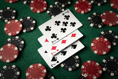 Playing cards with a combination of three of a kind or set on a green table.. Stock Photos