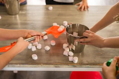Playing with children: hands on the table with marshmallows, bucket, shovel Stock Photos