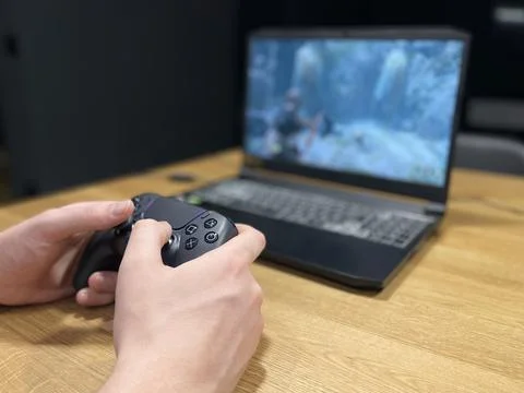 Playing computer game on laptop with joypad Stock Photos