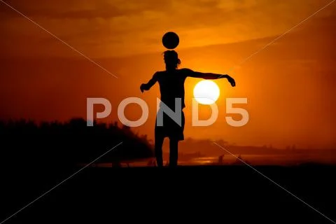 Playing football at the sunset on the beach Stock Photos