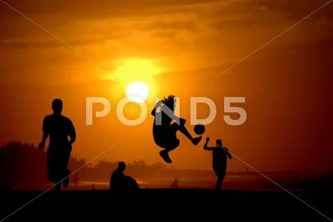 Playing football at the sunset on the beach Stock Photos