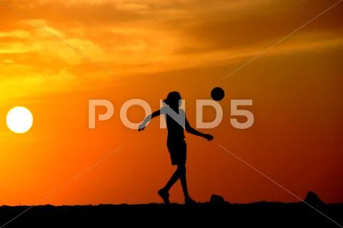 Playing football at the sunset on the beach Stock Photos