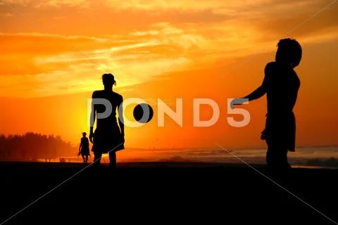 Playing football at the sunset on the beach Stock Photos