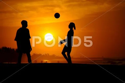 Playing football at the sunset on the beach Stock Photos