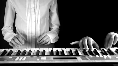Playing four hands on a synthesizer, performing the work as a Duo Stock Footage 131432613