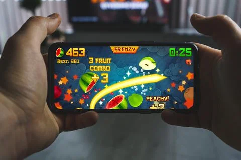 Playing Fruit ninja mobile game. Point of view gaming on smartphone Stock Photos