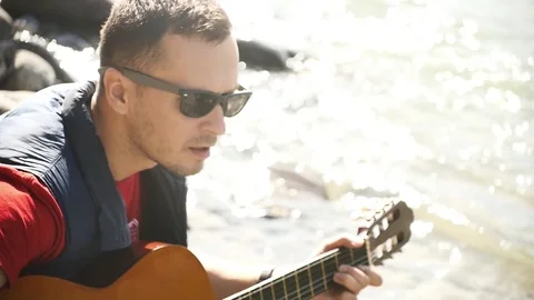 Playing the guitar on the background of glare from the water Stock Footage 80278895
