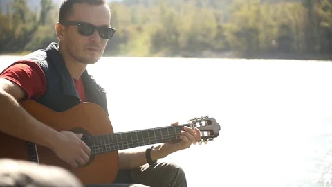 Playing the guitar on the background of glare from the water Stock Footage 80278943
