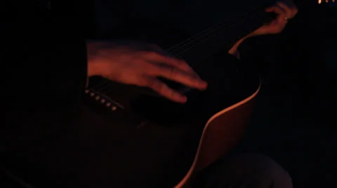 PLAYING THE GUITAR OUTSIDE WITH SHADOWS OF A FIRE ON GUITAR Stock Footage 35731518