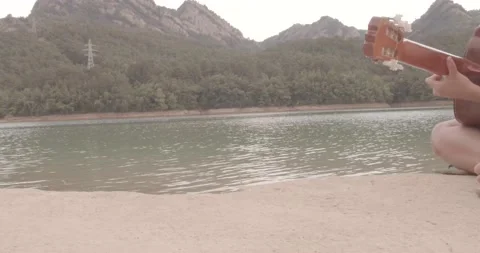 Playing guitar by the river Stock Footage 171175568