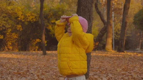 Playing hide and seek. Funny young girl hiding from somebody. Playing outside. Stock Footage 99859055